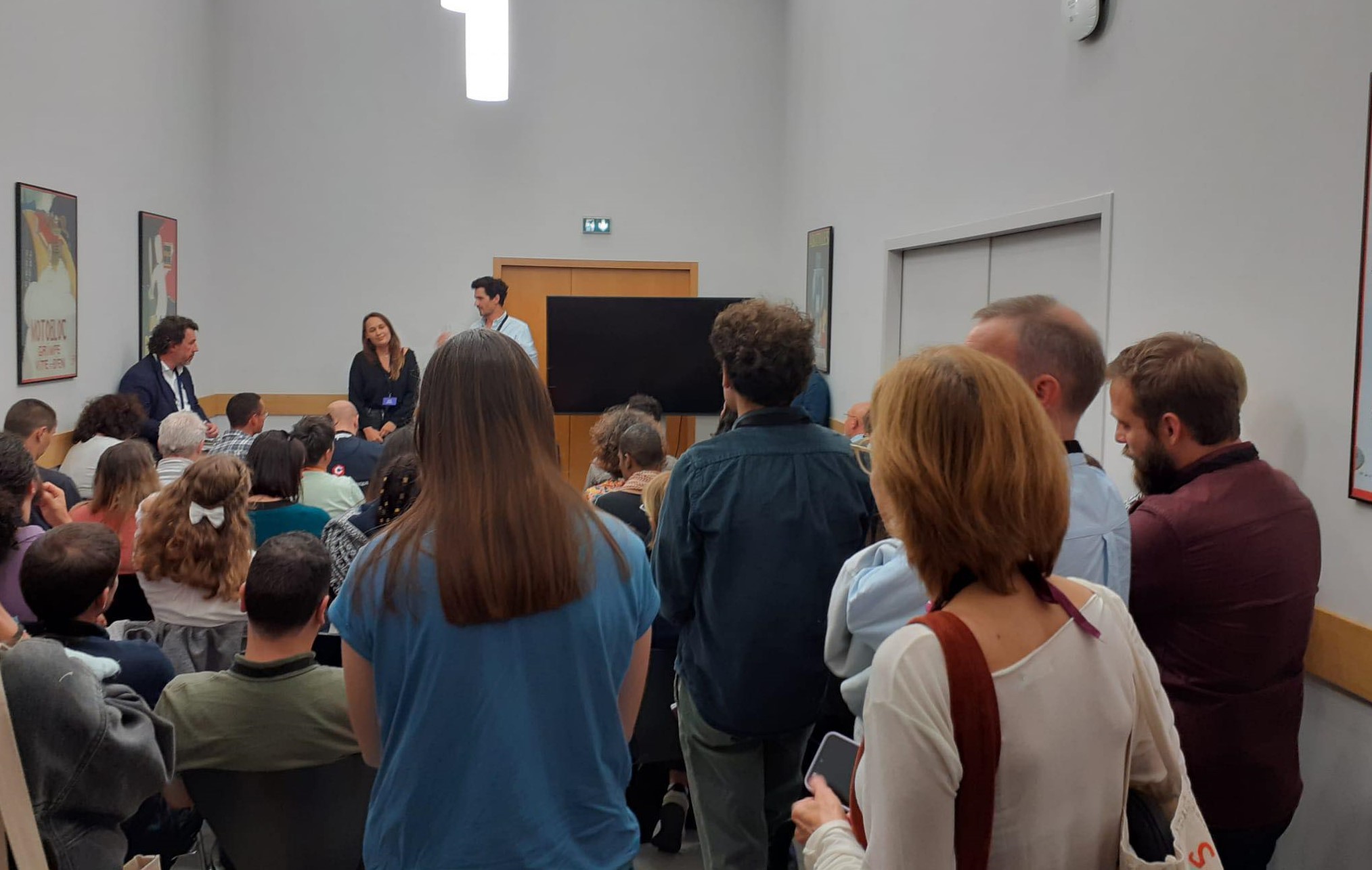 NEC 2023 - photo des intervenants prise depuis le fond du public pendant le retex dédié à ChatGPT et à la médiation numérique