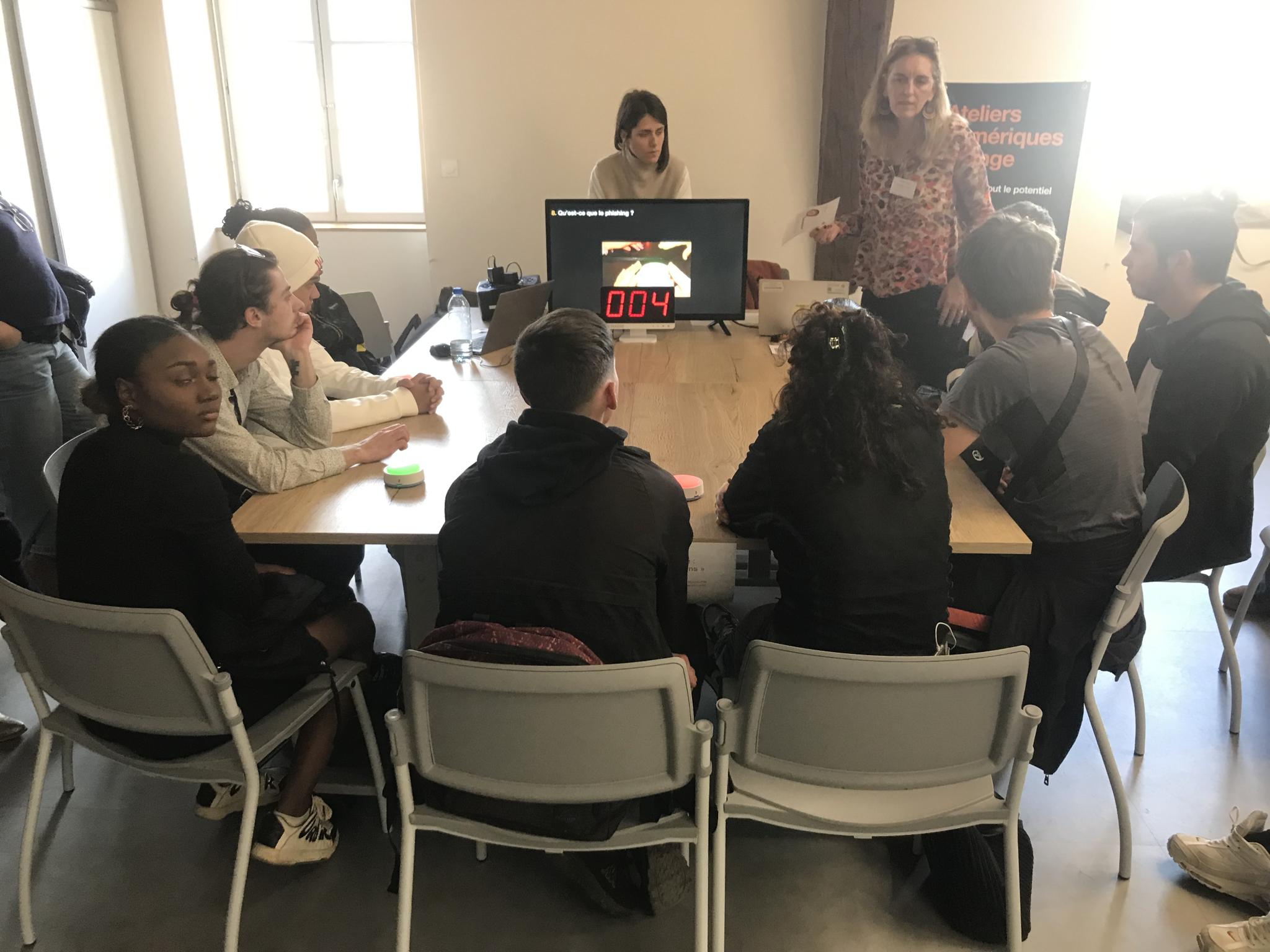 Visuel d'un atelier de médiation autour de la cybersécurité, où l'on voit les participants assis autour d'une table sur laquelle un écran servant de support d'échange et de présentation est posé.